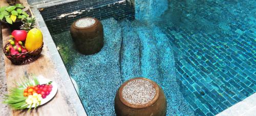 a swimming pool with a bowl of fruit and a plate of food at Sarina Boutique Hotel in Phnom Penh