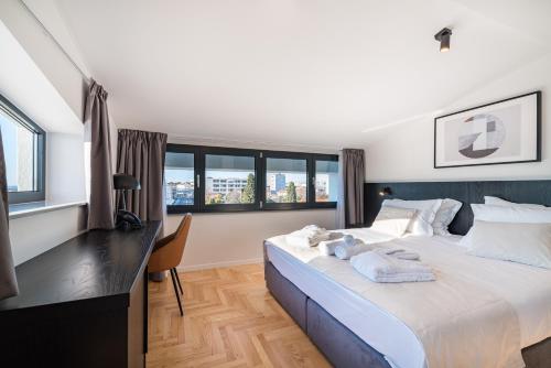 a bedroom with a large bed with a desk and windows at Miramare Hotel in Zadar