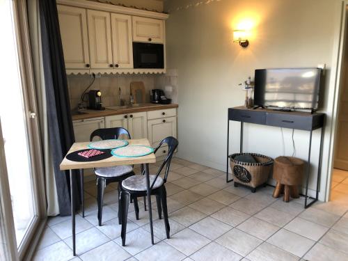 une cuisine avec une table et des chaises et une télévision dans l'établissement Studio les pieds dans l'eau, à Duingt