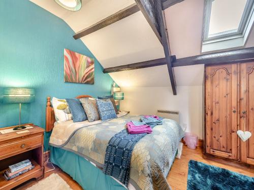 Un dormitorio con una cama con paredes azules y una ventana en Ty Llaethdy - Oac, en Gowerton