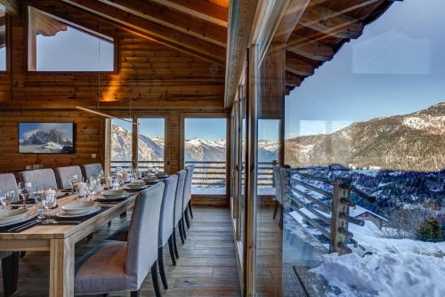 a dining room with a table and chairs and mountains at Chalet la Chance in La Tzoumaz