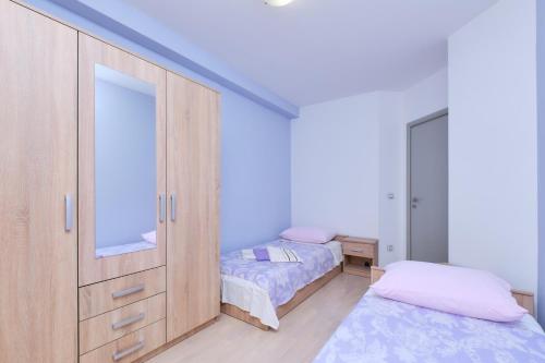een slaapkamer met 2 bedden en een kast met een spiegel bij Apartment Dino 1 in Mali Lošinj