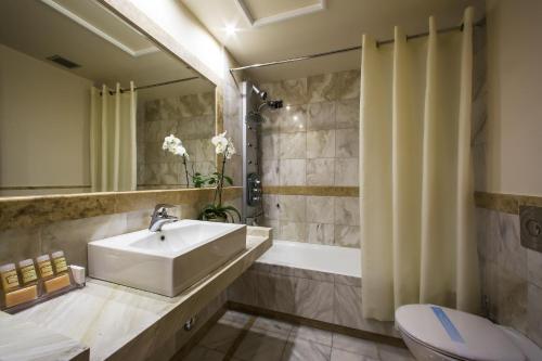 a bathroom with a sink and a tub and a toilet at Dekelia Hotel in Athens