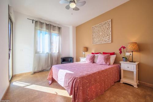 a bedroom with a bed with a pink bedspread and a window at Apartamentos Madrid in Torrevieja