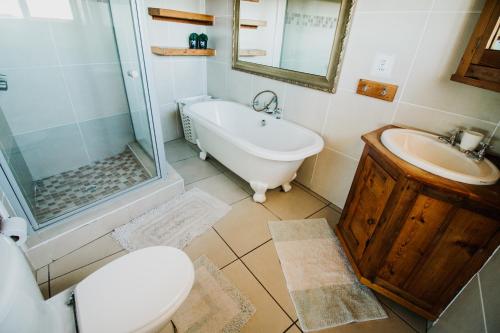 a bathroom with a tub and a toilet and a sink at Oceans Voice in Jeffreys Bay