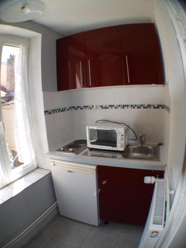 une petite cuisine avec un micro-ondes et un évier dans l'établissement Superbe studio dans quartier calme, à Nancy