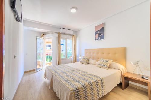 a white bedroom with a large bed and a window at Hotel Madrid in Torrevieja