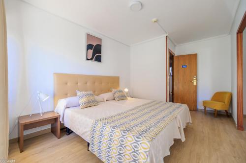 a bedroom with a large bed and a chair at Hotel Madrid in Torrevieja