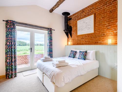 a bedroom with a bed and a brick wall at Freds Barn in Swanton Abbot