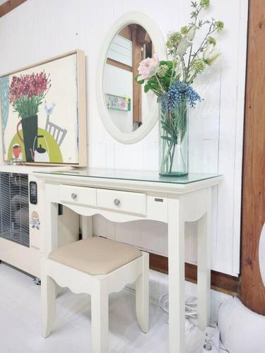 a white desk with a vase of flowers and a mirror at Hyanggyo-gil, Seonwooga in Jeonju