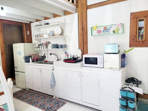 a white kitchen with a microwave and a refrigerator at Hyanggyo-gil, Seonwooga in Jeonju