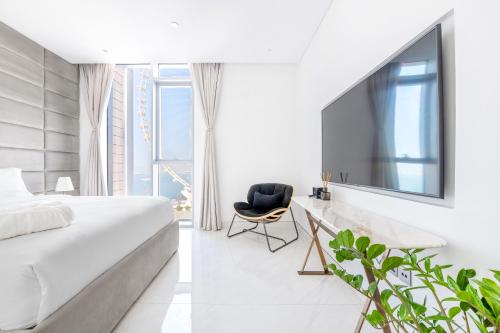 a bedroom with a bed and a chair and a tv at Spectacular 3 BR condo with maids room facing the Dubai Eye in Dubai