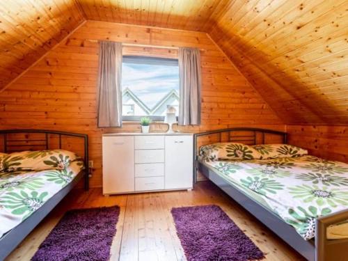 2 łóżka w pokoju z oknem i fioletowymi dywanami w obiekcie Domki letniskowe Nadia 1 we Władysławowie