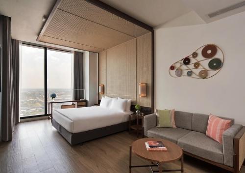 um quarto de hotel com uma cama e um sofá em Ad Lib Hotel Khon Kaen em Khon Kaen