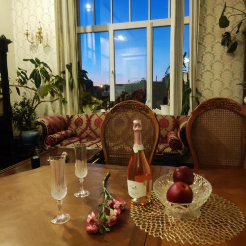 a bottle of wine sitting on a table with some apples at Ventspils apartamenti pie Rātslaukuma in Ventspils