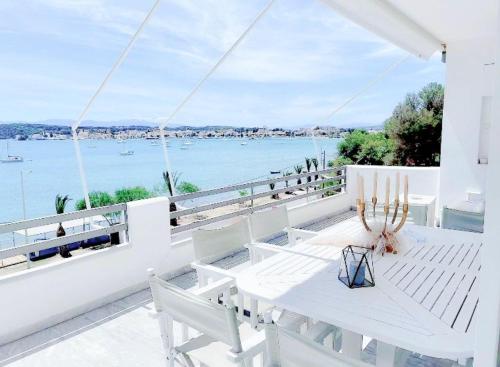 a white table and chairs on a balcony overlooking the water at Fairy home Porto Heli in Porto Heli