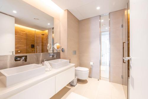 a bathroom with a sink and a toilet and a mirror at Spectacular 3 BR condo with maids room facing the Dubai Eye in Dubai