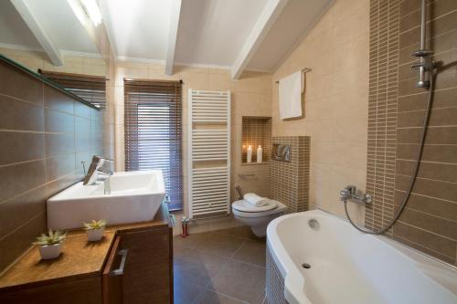 a bathroom with a tub and a sink and a toilet at Villa Rina in Nydri