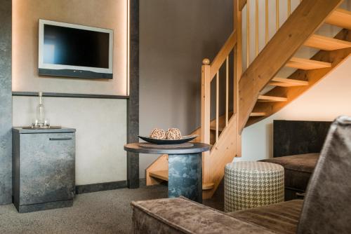 a living room with a staircase and a table at Klein Fein Hotel Anderlahn in Parcines