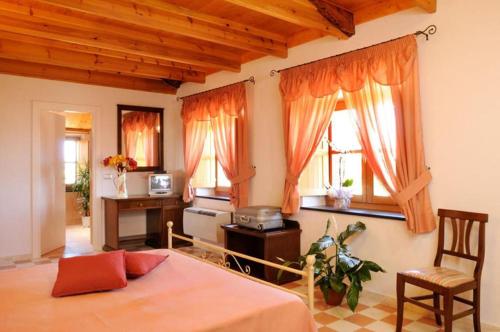 a bedroom with a bed and a desk and two windows at Villa Maria Pia in Alghero