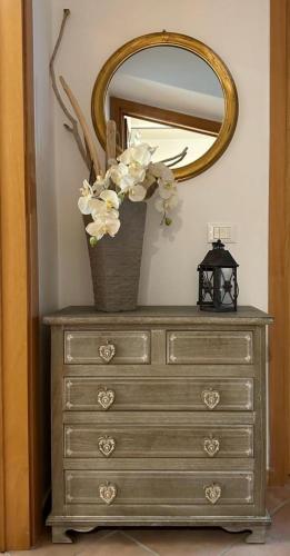 a dresser with a mirror and a vase with flowers on it at La Casa di Filippo in Quercianella