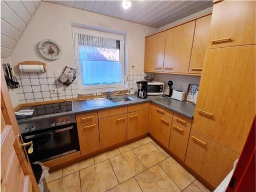 cocina con armarios de madera, fregadero y ventana en Meerhaus Hieve en Emden