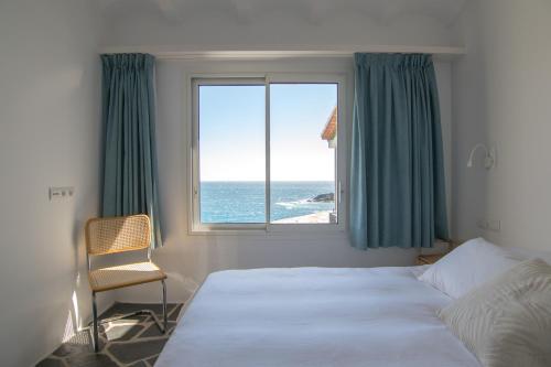 um quarto com uma cama e uma janela com o oceano em Sa Guineu em Cadaqués