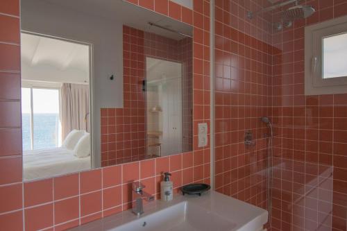 La salle de bains est pourvue de carrelage rouge, d'un lavabo et d'un miroir. dans l'établissement Sa Guineu, à Cadaqués