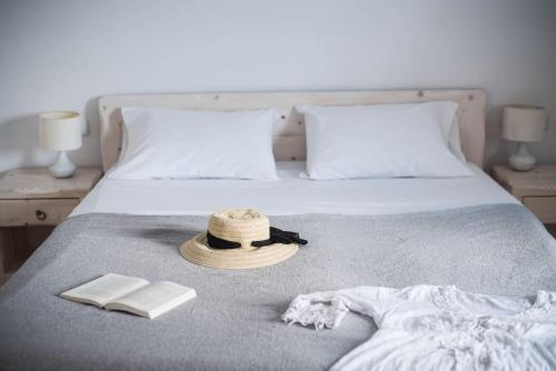 a bed with a straw hat and a book and a book at White Wave Villa, 3min walk from beach in Kamari