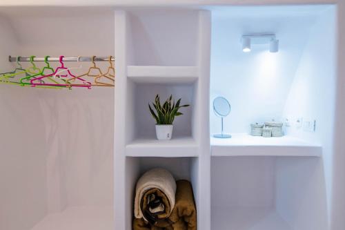 a bathroom with white shelves and a mirror and a plant at White Wave Villa, 3min walk from beach in Kamari