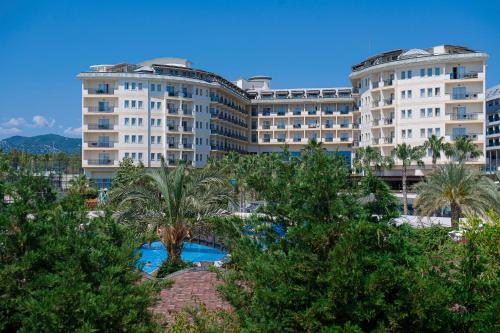 a large building with trees in front of it at Mukarnas Spa & Resort Hotel in Okurcalar