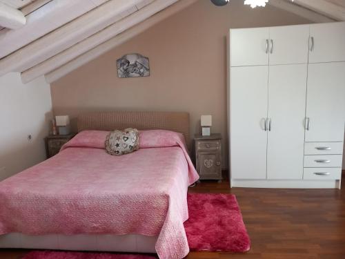 um quarto com uma cama rosa e armários brancos em Billy house em Acireale