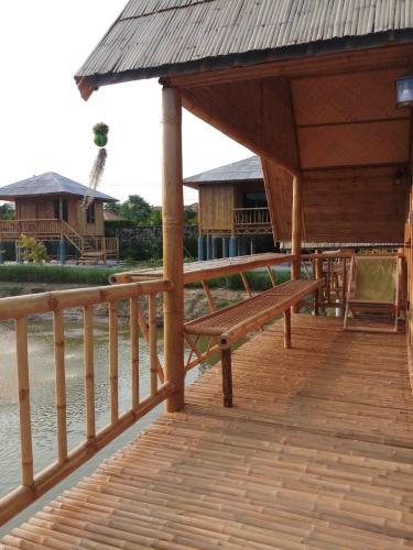 a wooden deck with a bench next to the water at คูณ-เนื่อง ฟาร์ม สเตย์ หัวหิน Koon & Nueang Farm Stay Hua Hin in Ban Bo Fai