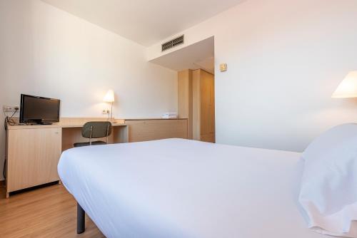 a bedroom with a white bed and a tv at Hotel Basic in Vilafranca del Penedès