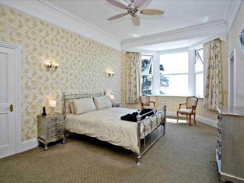 a bedroom with a bed and two chairs and a window at Riviera Mansion, Torquay in Torquay