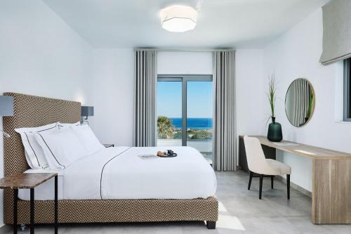 Habitación de hotel con cama, escritorio y ventana en Quattro Suites en Monemvasia