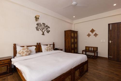 a bedroom with a large bed with white sheets at Yogved Hospitality & Resort in Rishīkesh