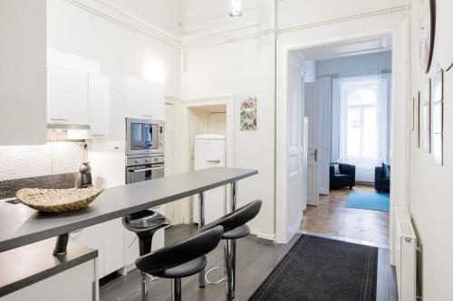 ブダペストにあるElisabeth 52 Apartmentの白いキャビネット付きのキッチン、カウンター(スツール付)