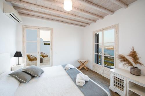 1 dormitorio blanco con 1 cama grande y ventanas en MYKONOS-ORNOS -VILAS ANGEL ALICE DEMI -POOL HOLIDAYS with VIEW, en Mykonos ciudad