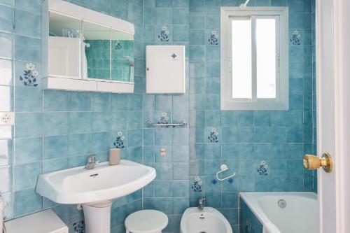baño de azulejos azules con lavabo y aseo en Edificio Flamingo, en Gandía