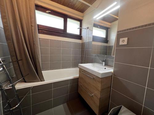 a bathroom with a tub and a sink and a bath tubermottermott at Elan 19 - Appartement 3 chambres in La Clusaz