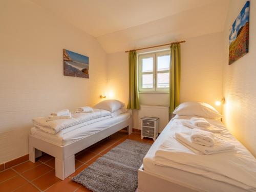 two beds in a small room with a window at Feriendorf Rugana - Komfort Appartement mit 2 Schlafzimmern und Terrasse D03 in Dranske