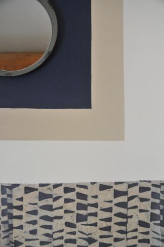 a mirror on a wall next to a rug at Le Mas des Perrines Maison d’Hôtes in Pernes-les-Fontaines