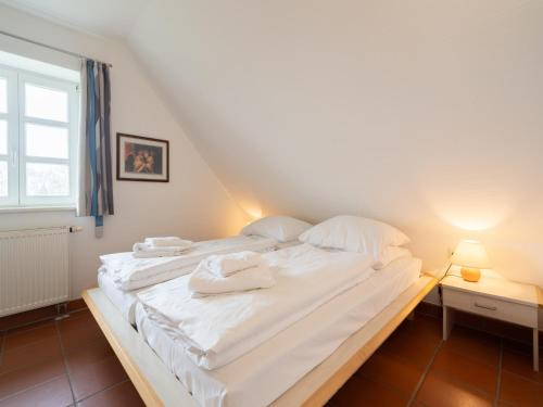 a bedroom with a bed with white sheets and towels at Feriendorf Rugana - Klassik Appartement mit 1 Schlafzimmer D15 in Dranske