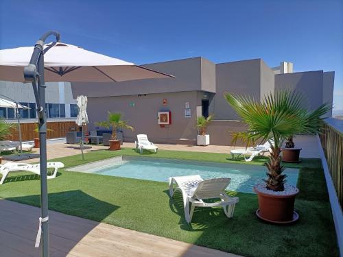 una piscina con sillas, una palmera y una sombrilla en Hotel BESTPRICE Alcalá en Madrid