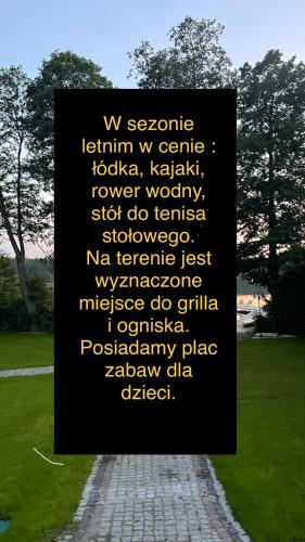 a sign in a park with writing on it at Domki nad jeziorem Kazub in Cieciorka