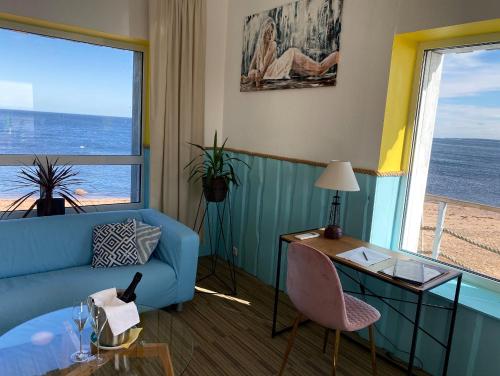 a living room with a blue couch and a desk and windows at Vergi Sadam & Restoran Wirkes' in Vergi
