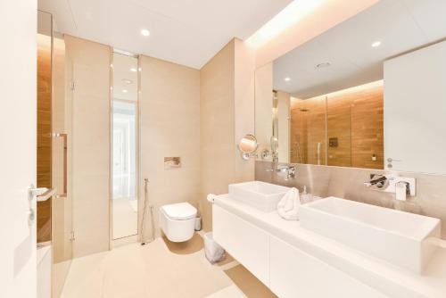 a white bathroom with two sinks and a toilet at Luxe 3 BR Oceanfront Apt with maids room in the heart of Bluewaters Island in Dubai