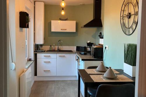 une cuisine avec des placards blancs et une horloge murale dans l'établissement la petite terrasse d’Arthur; appartement terrasse à 50m de la mer, à Le Portel