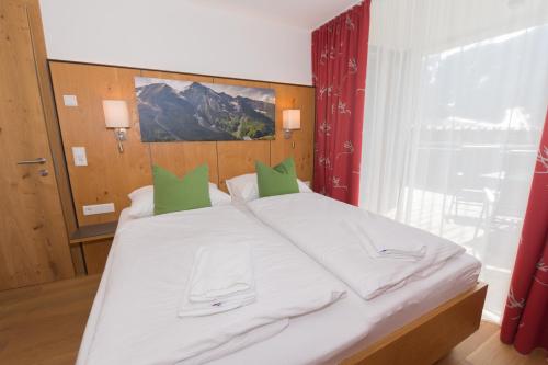 a bedroom with a large white bed with green pillows at Apartment am Sonnenhang - Top 3 in Neukirchen am Großvenediger